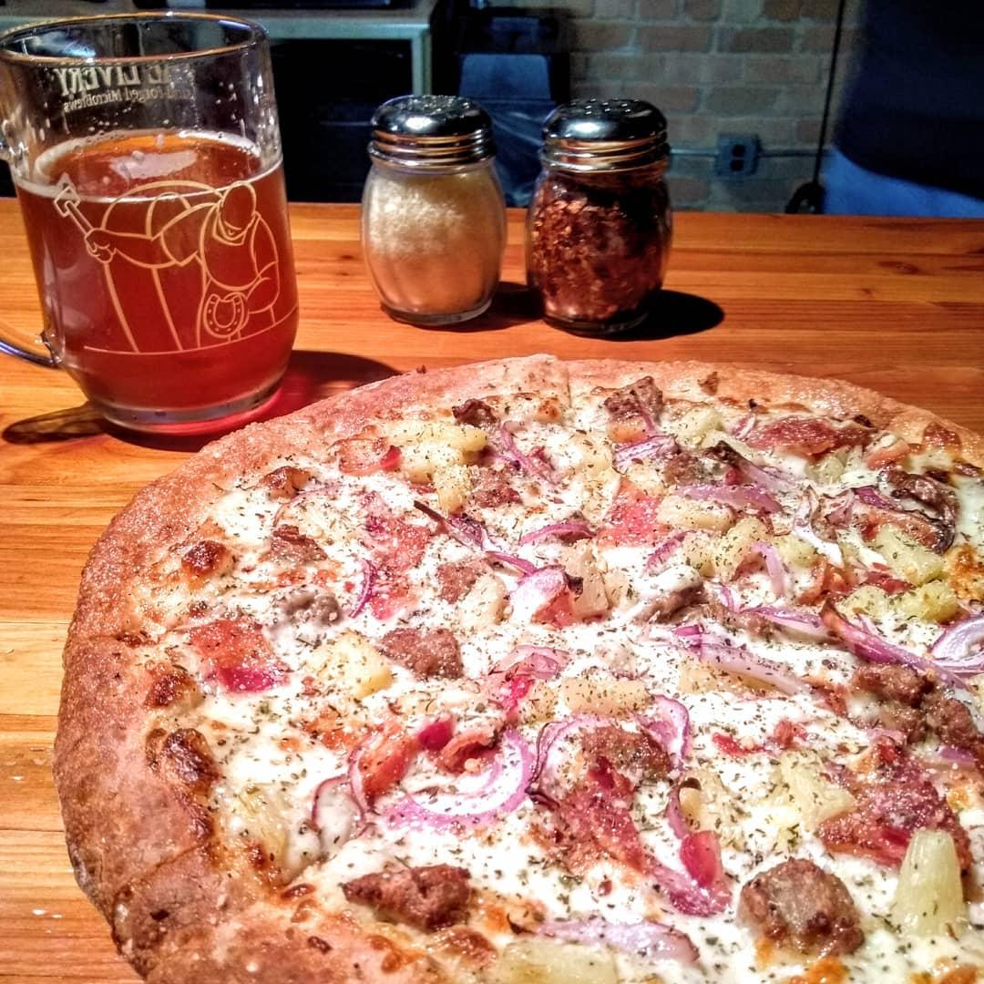 A pizza pie with a mug of beer in the background