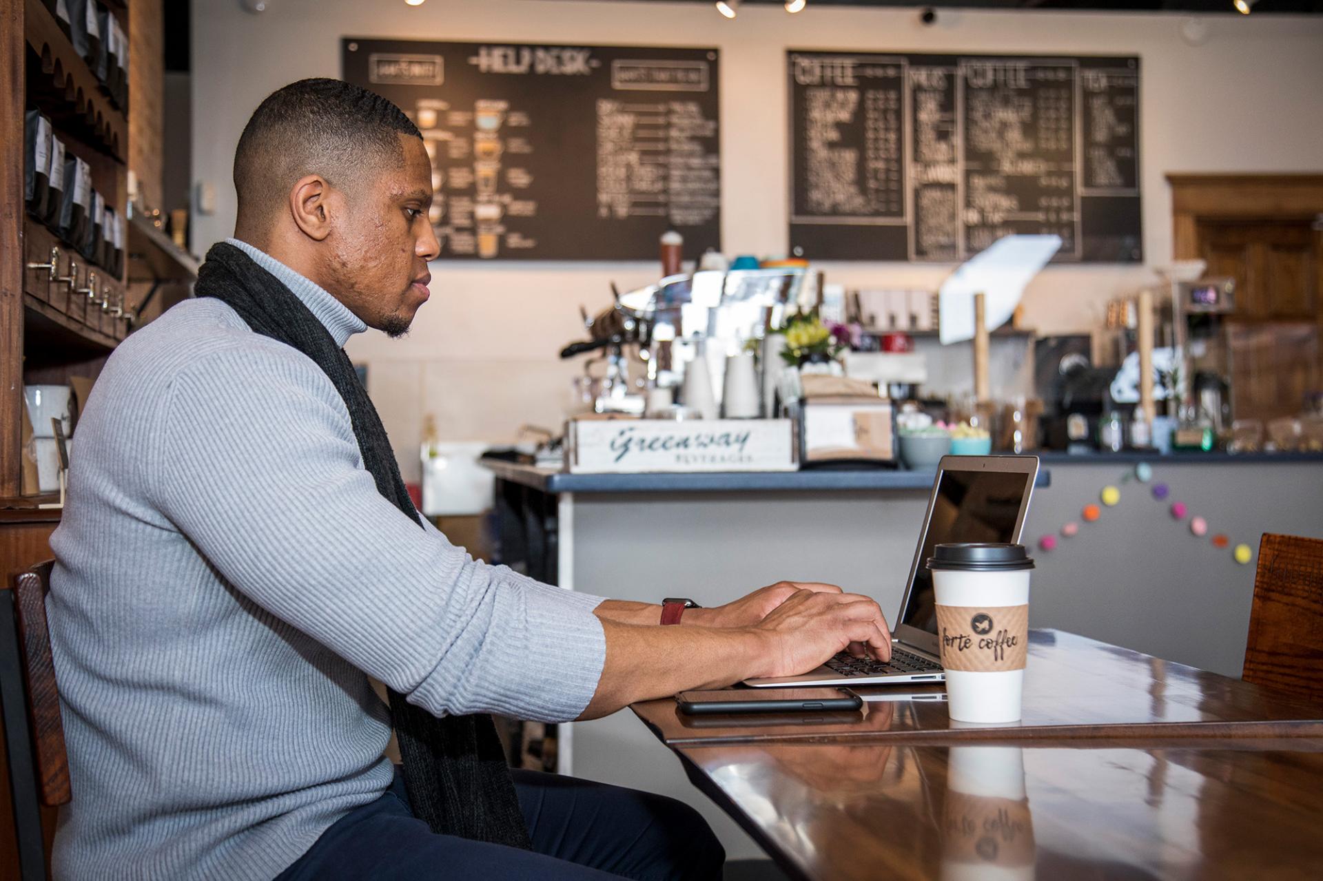 A man working on his laptop at a coffee shop