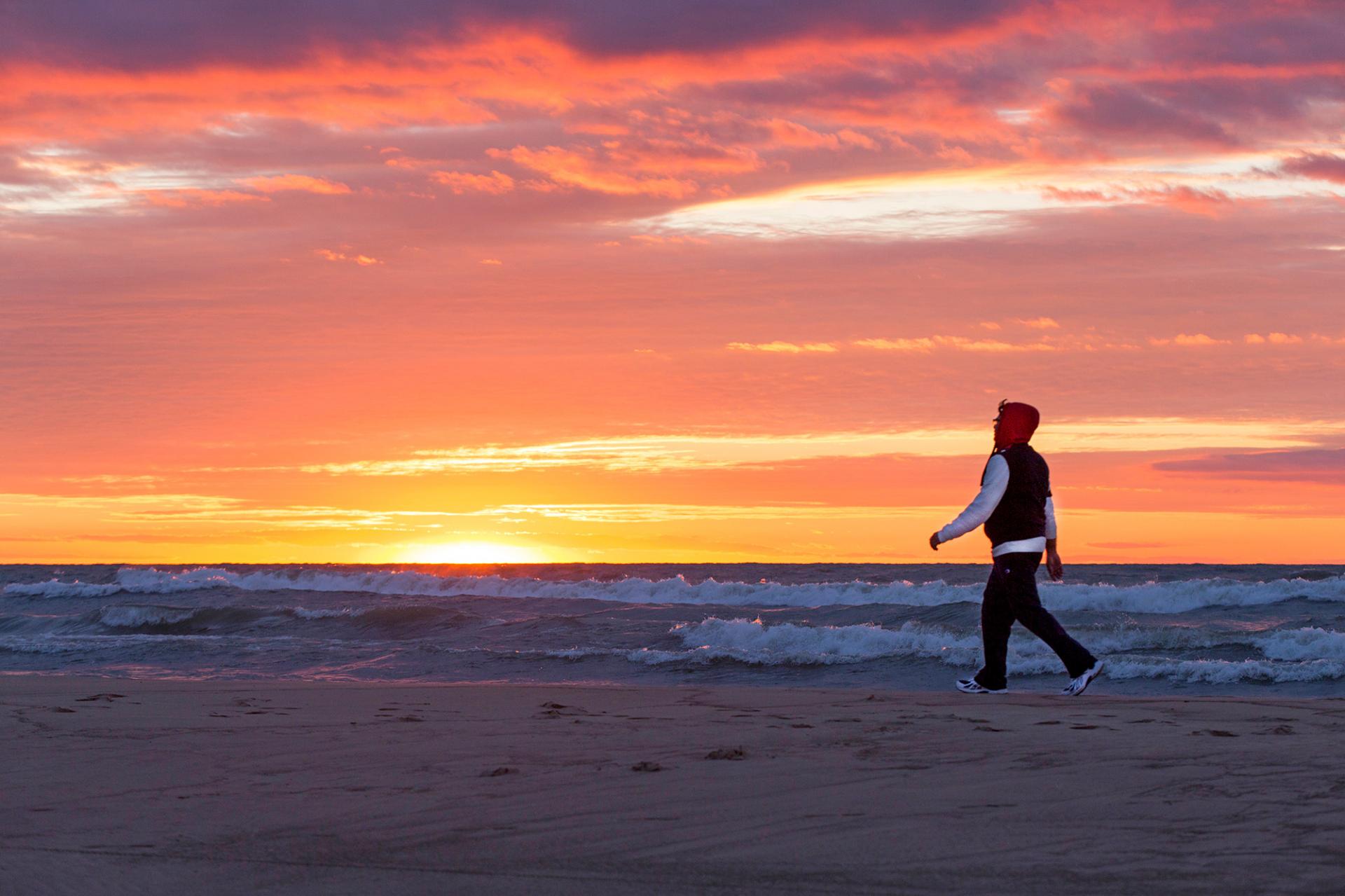 A person walking on the beach at sunset