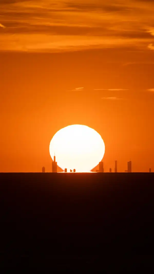 The Chicago skyline silhoutted in front of the setting sun over Lake Michigan.