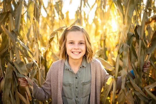A child standing in a corn maze.