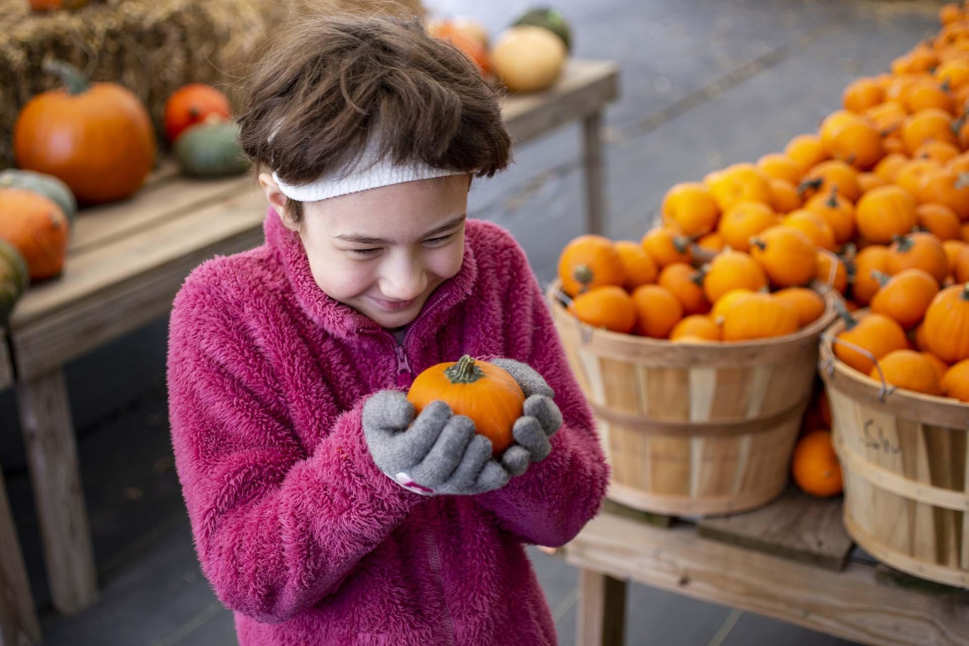 A child holding a small pumpkin.