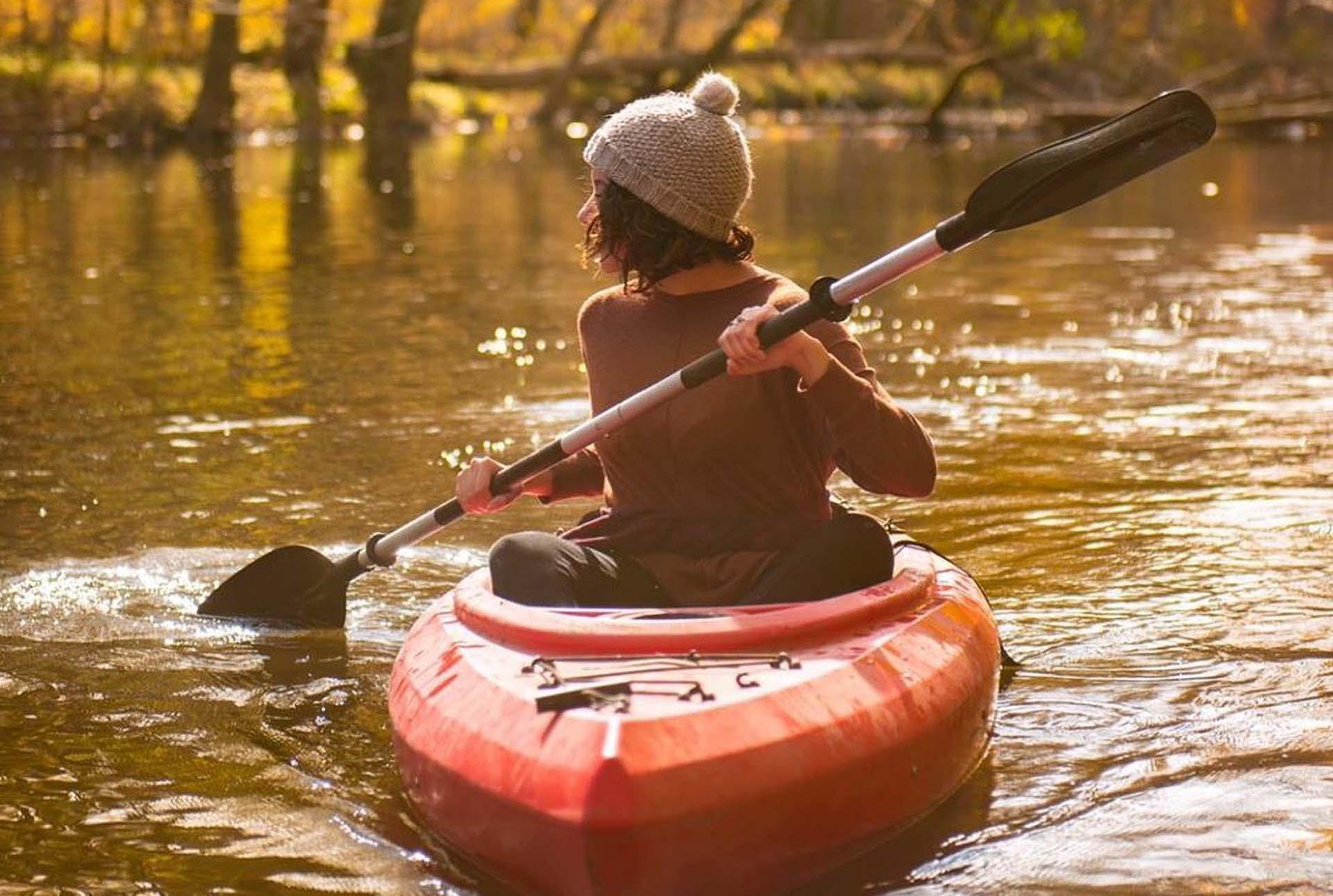A person kayaking a river in the fall.