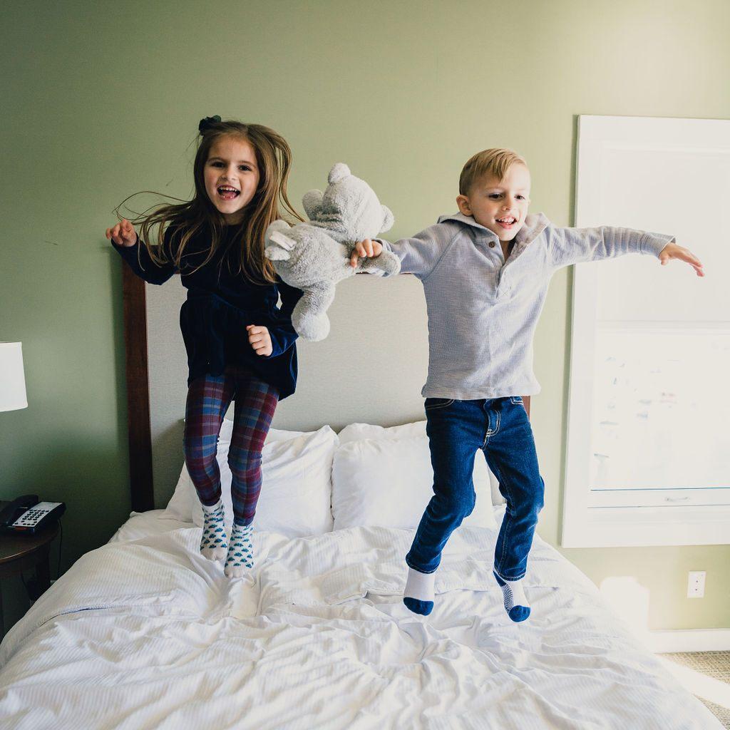 Kids jumping on a bed.