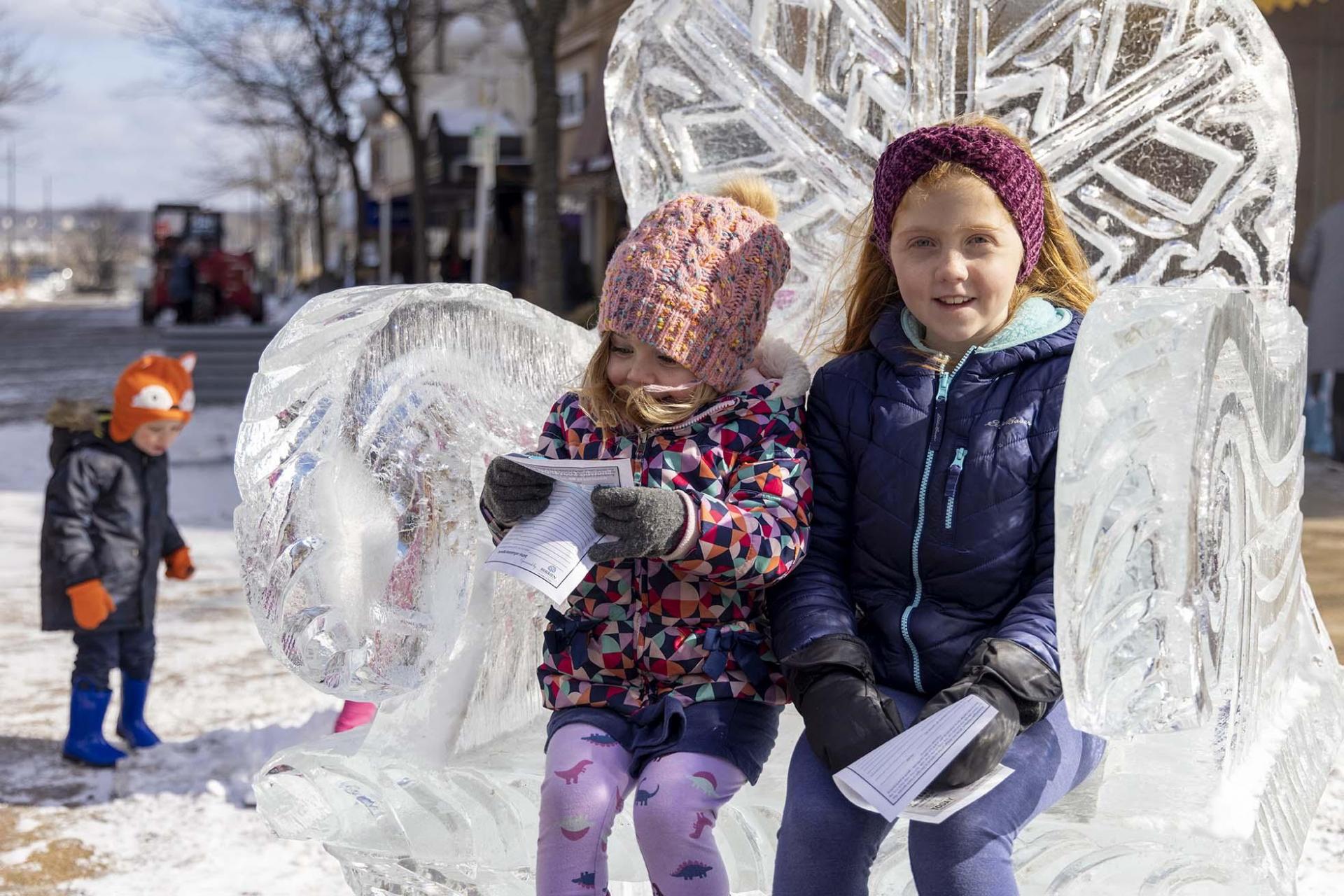 Two kids sitting on an ice chair.