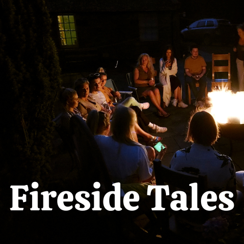 Group of people  in the dark sitting around a campfire with the words "Fireside Tales" overlaid