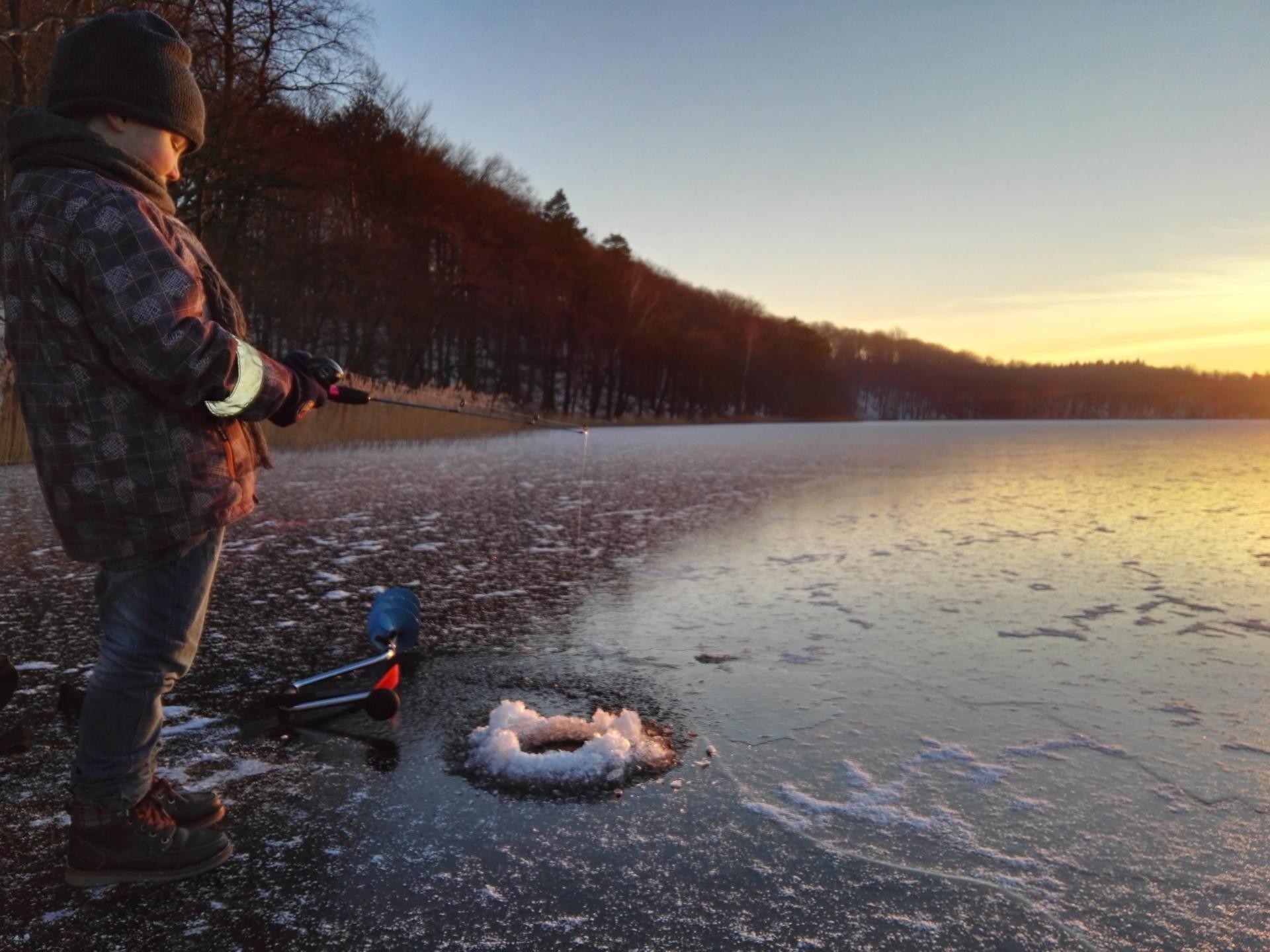 child ice fishing on a frozen lake
