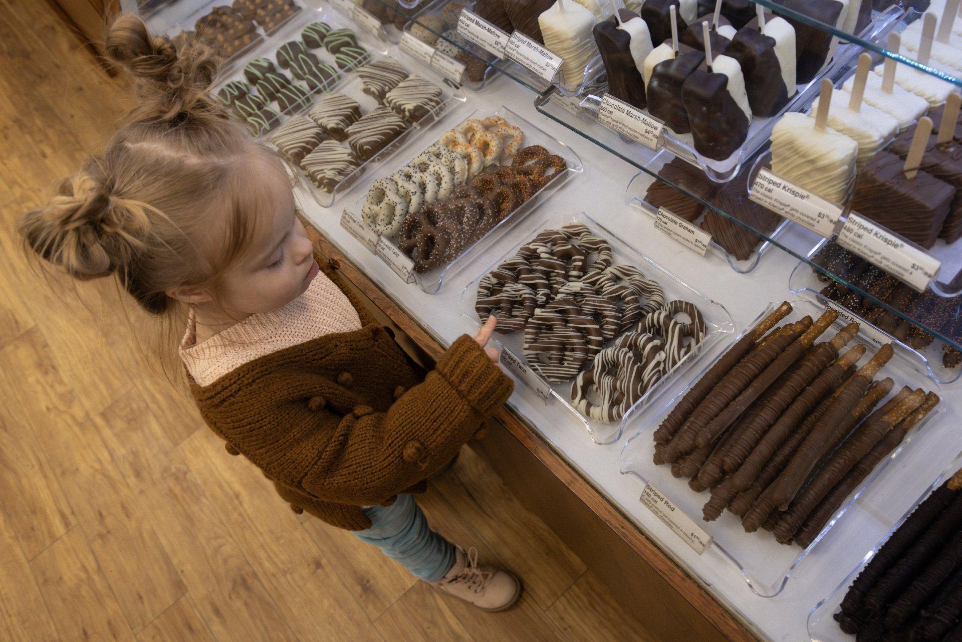 young child in front of kilwins chocolate case larger