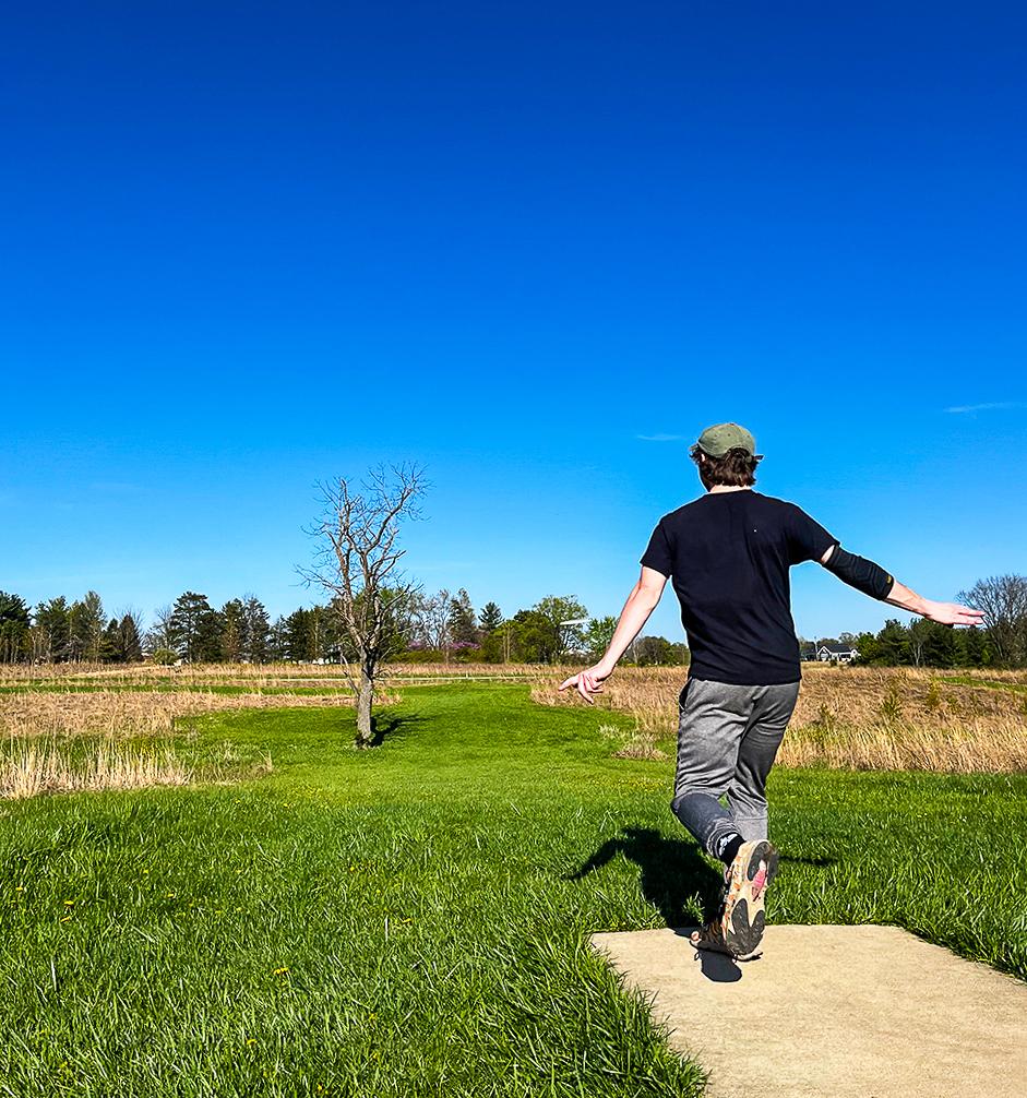 man throwing disc golf disc on course