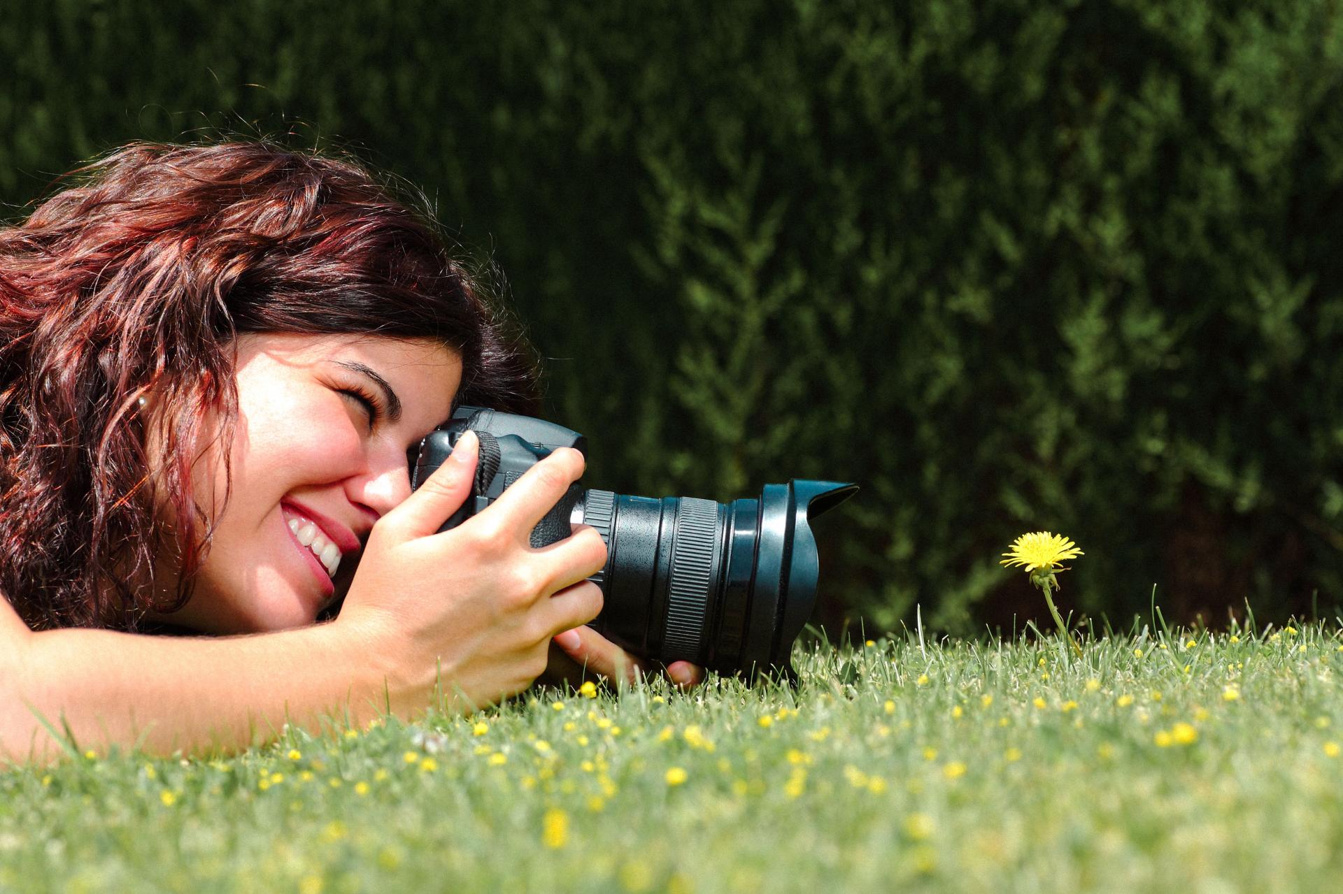 A-woman-taking-a-picture-of-a-dandelion-flower--