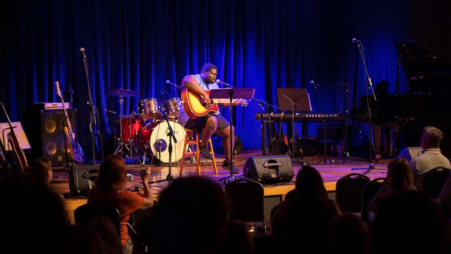 A man playing the guitar at The Acorn theather