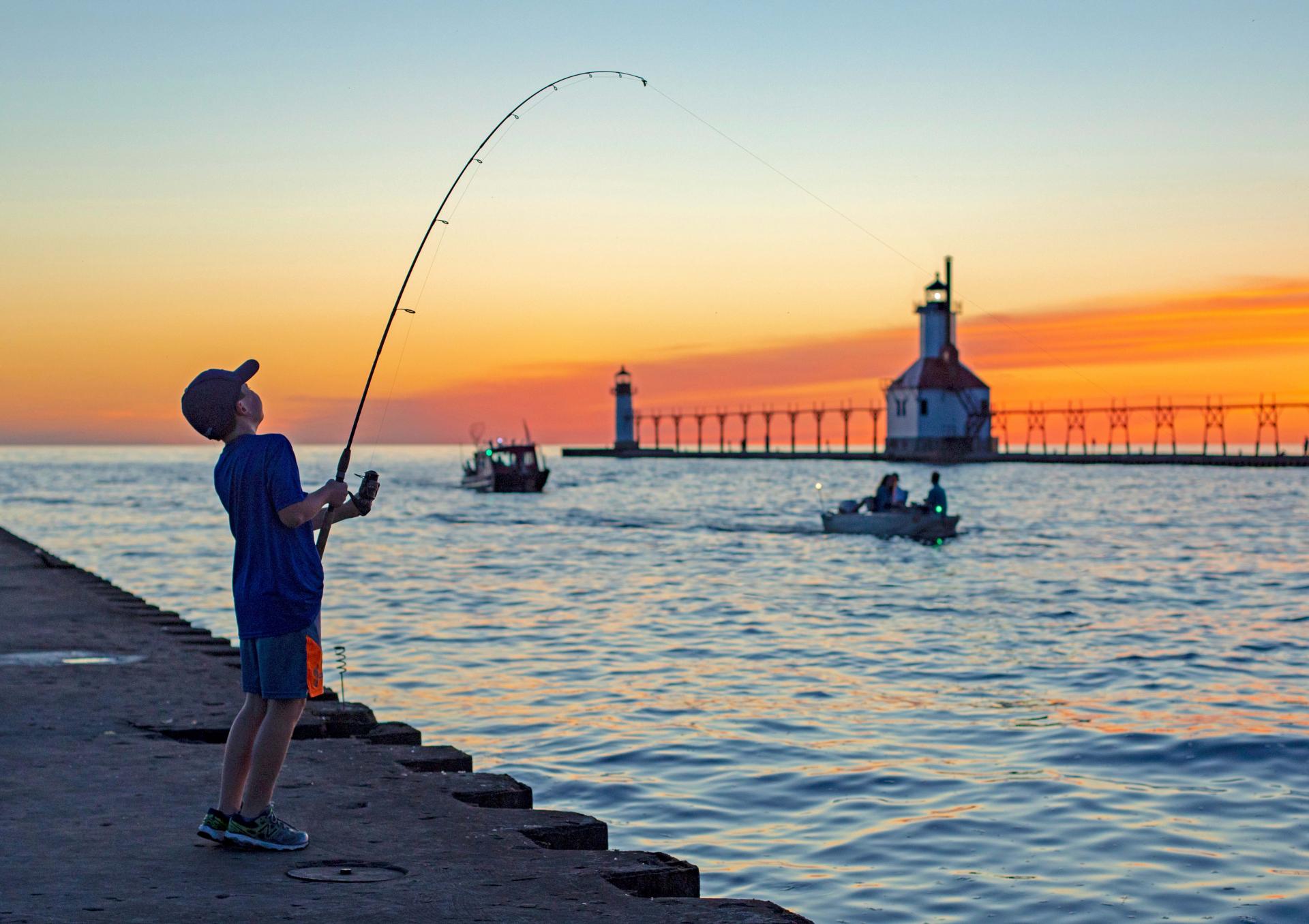 A-boy-fishing-near-the-lighthouse-at-sunset