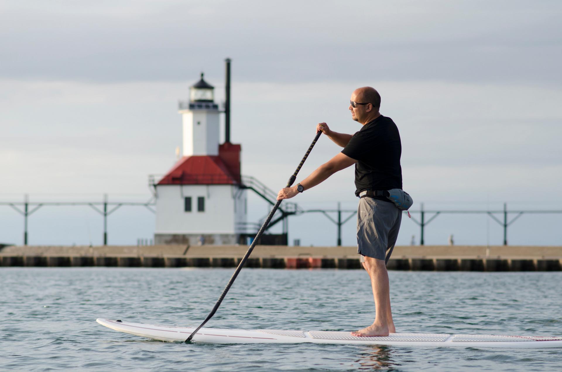 a man paddleboarding in front of st joseph lighthouse