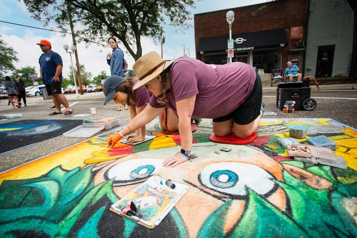 a woman drawing on the pavement for chalk the block in st. joseph 