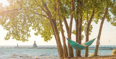 a hammock between trees at silver beach park with the lighthouse in the background