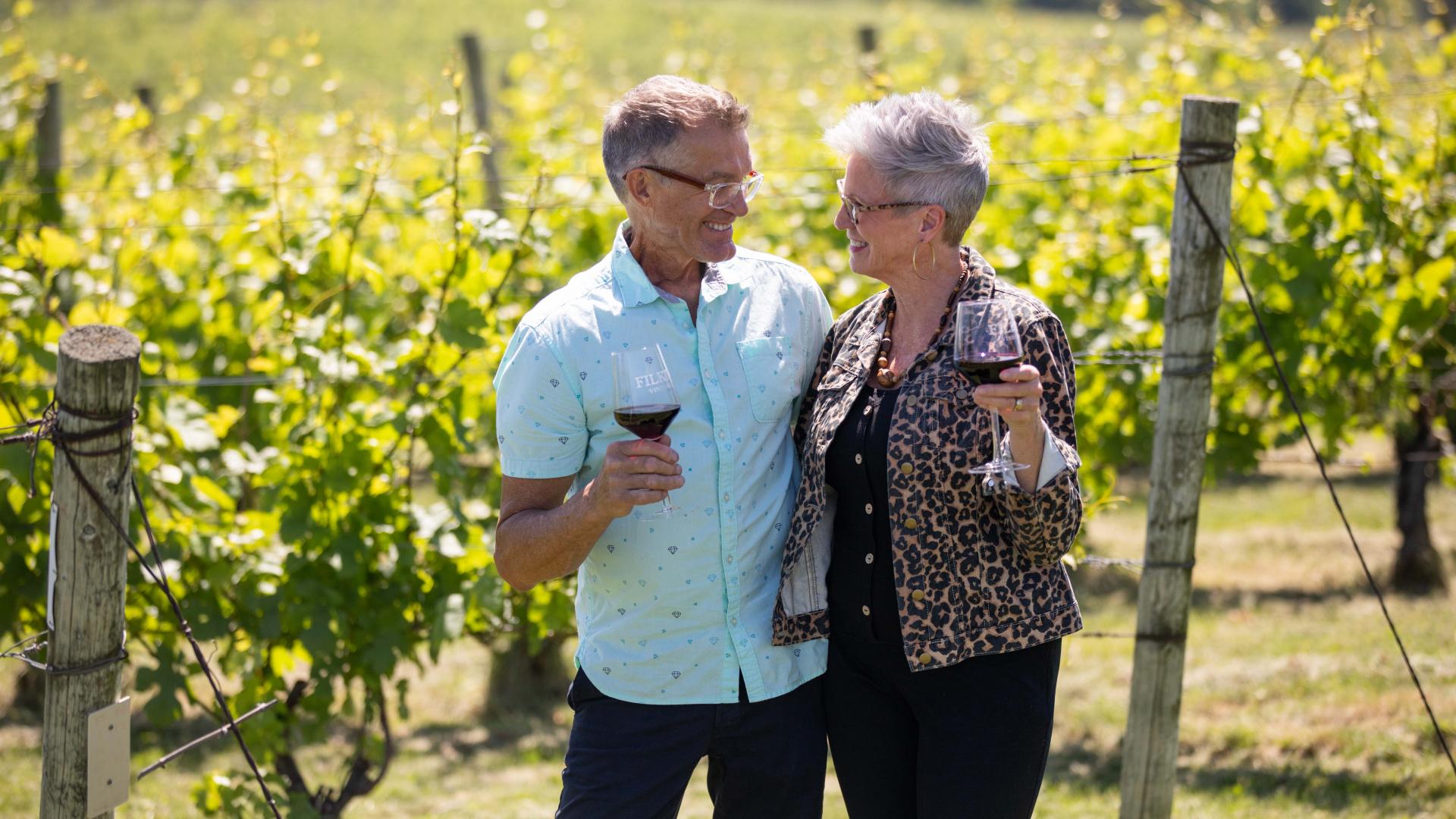 a couple tasting wine in a vineyard