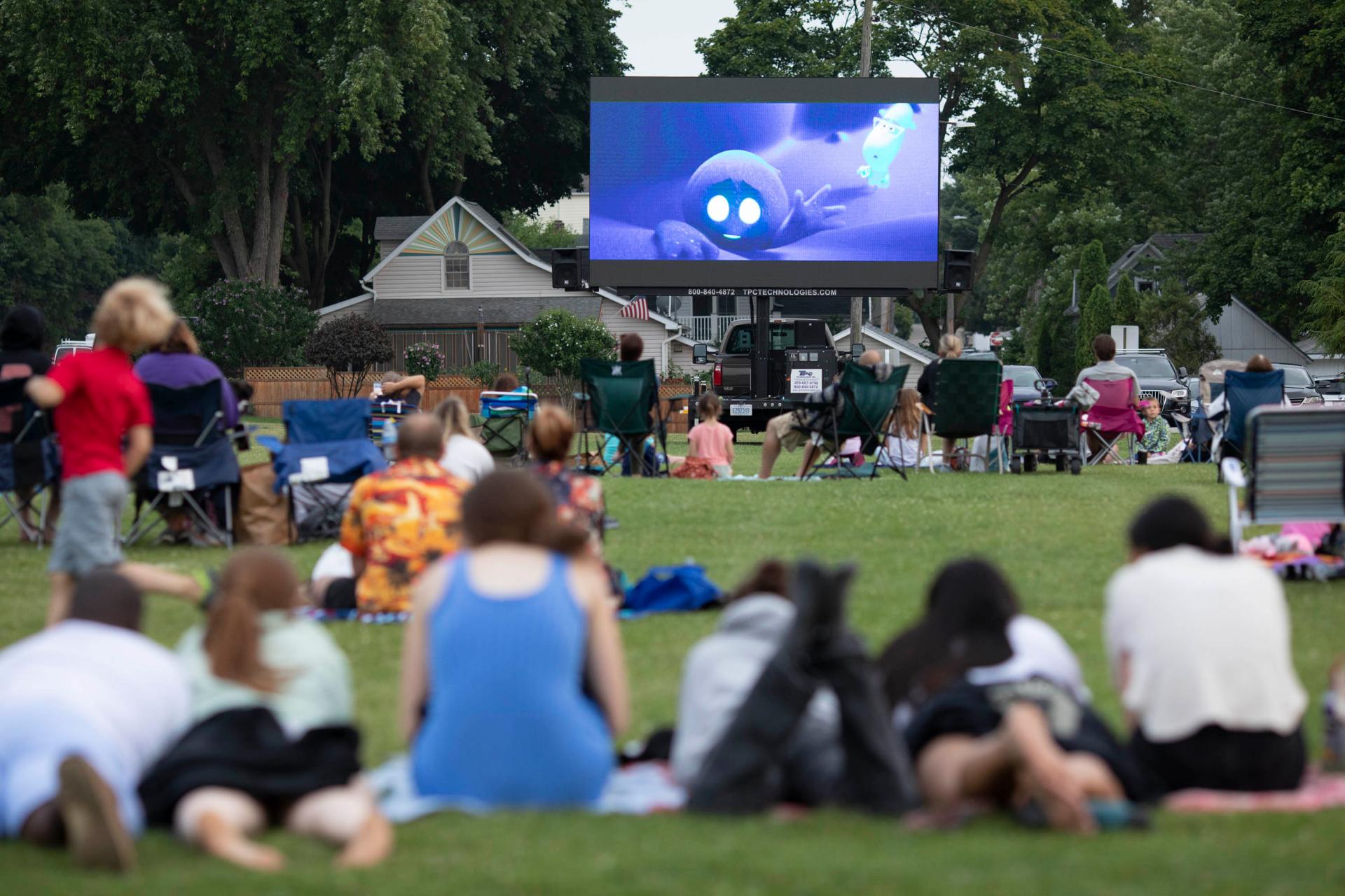 group of people sitting outside watching movies in the park