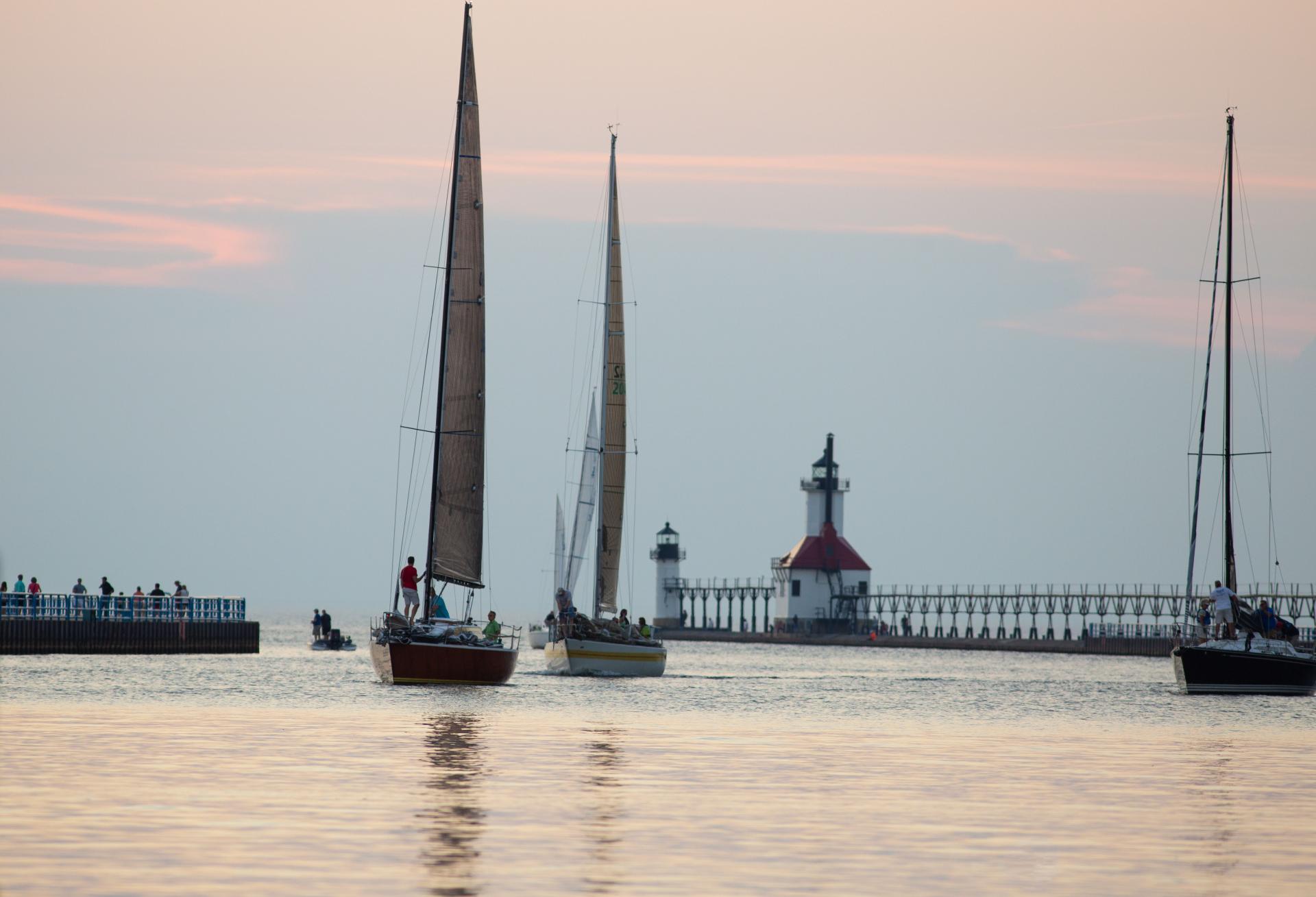 sailboats around the lighthouse near sunset