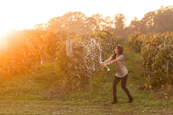 A person with wine in a vineyard.