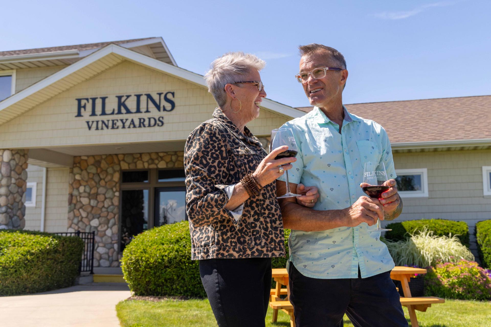 A couple drinking wine in front of Filkins Vineyards