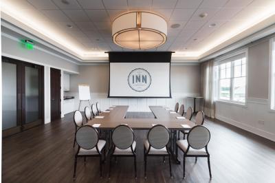 Meeting room set up in a U-shape configuration, facing a large screen, designed for presentations and collaborative discussions.