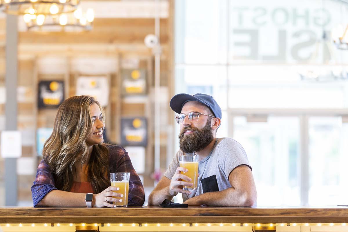 Two people enjoying beers at the bar at Ghost Isle Brewery.