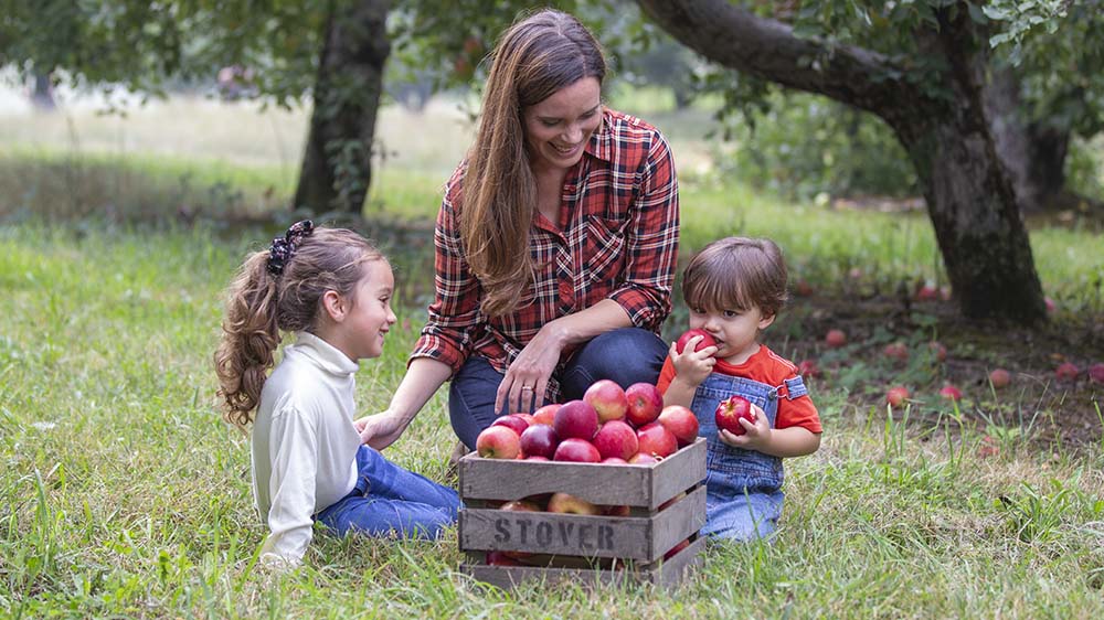 A parent and two children in an orchard. 