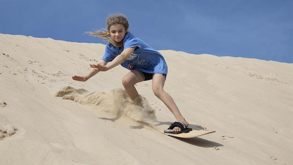 A person sandboarding at Warren Dunes State Park