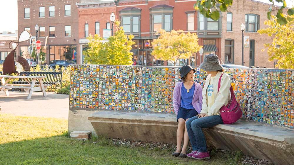 Two people sitting on a bench in the Benton Harbor Arts District.