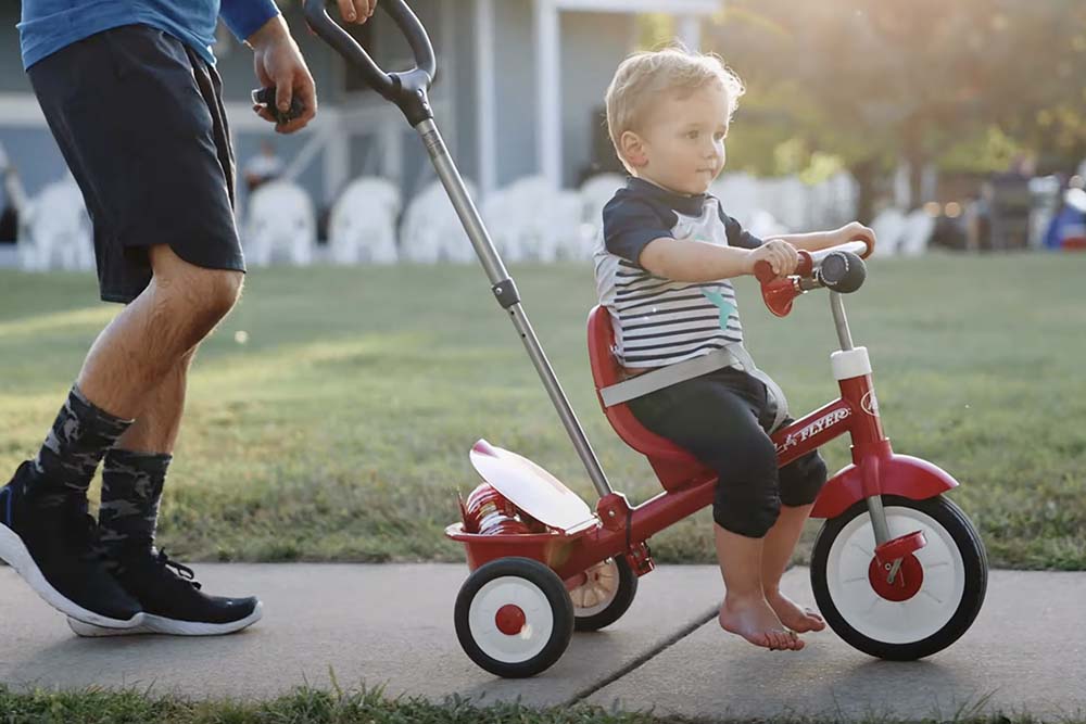 a person pushing a toddler's bike
