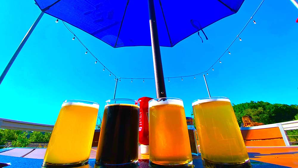 A flight of beers on a table outdoors.