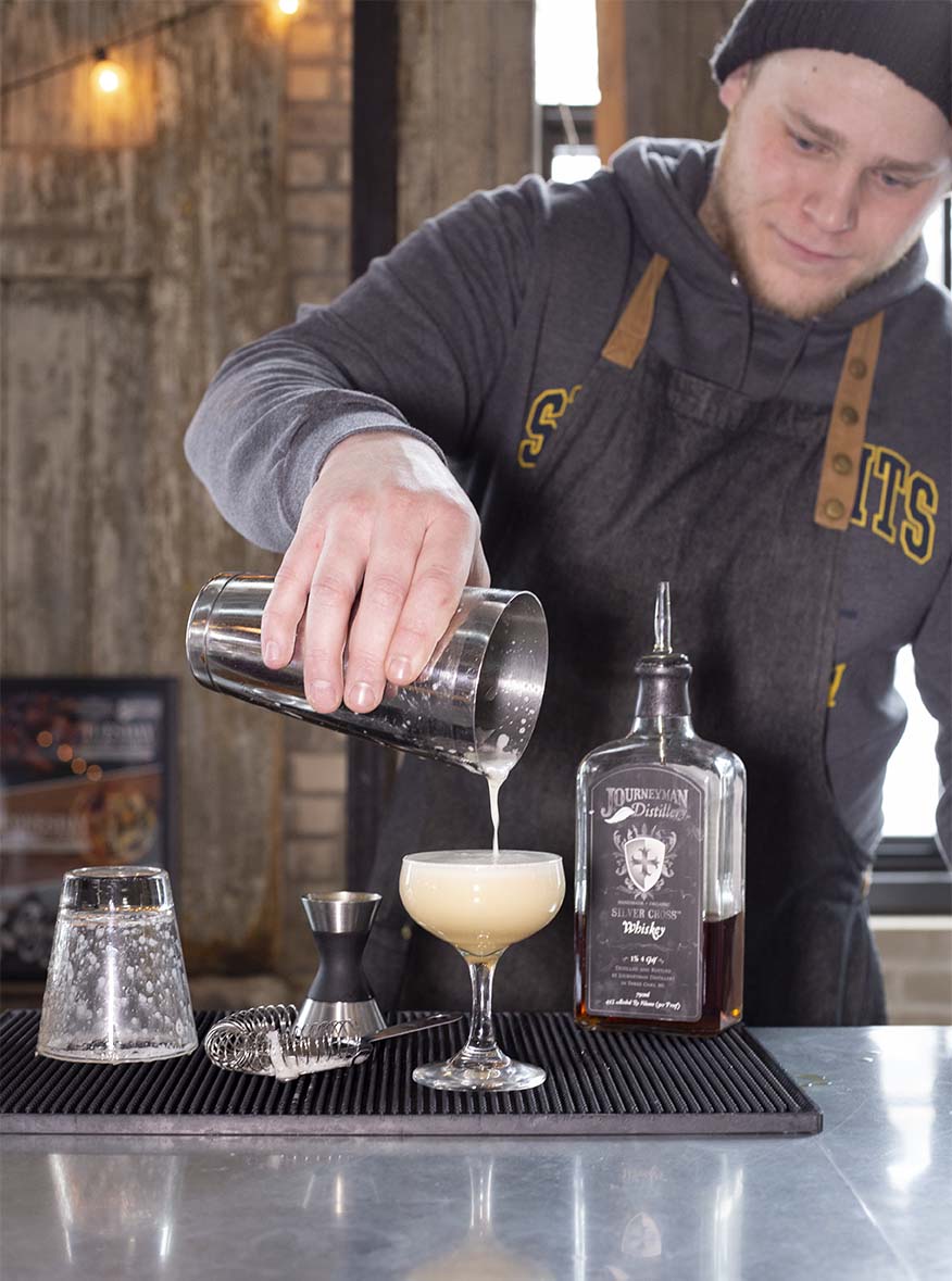 Bartender pouring a mixed drink at Journeyman Distillery