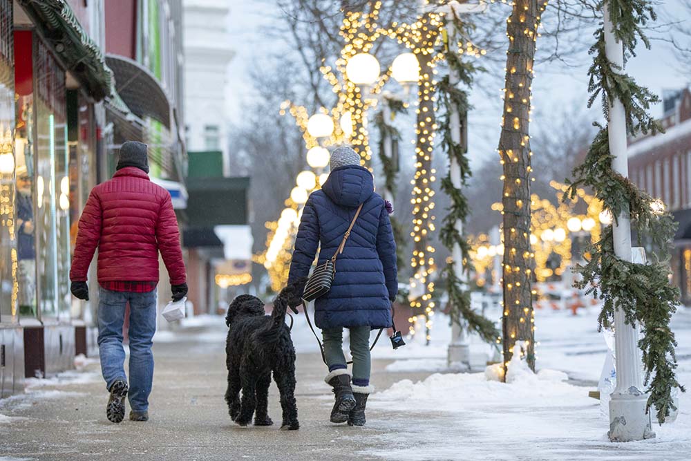 Two people and a dog walking in downtown St. Joseph, Michigan in the winter. 