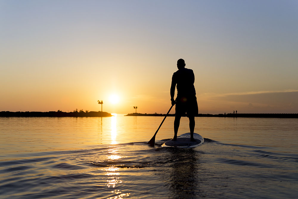 Man paddleboarding towards the Lake Michigan sunset.